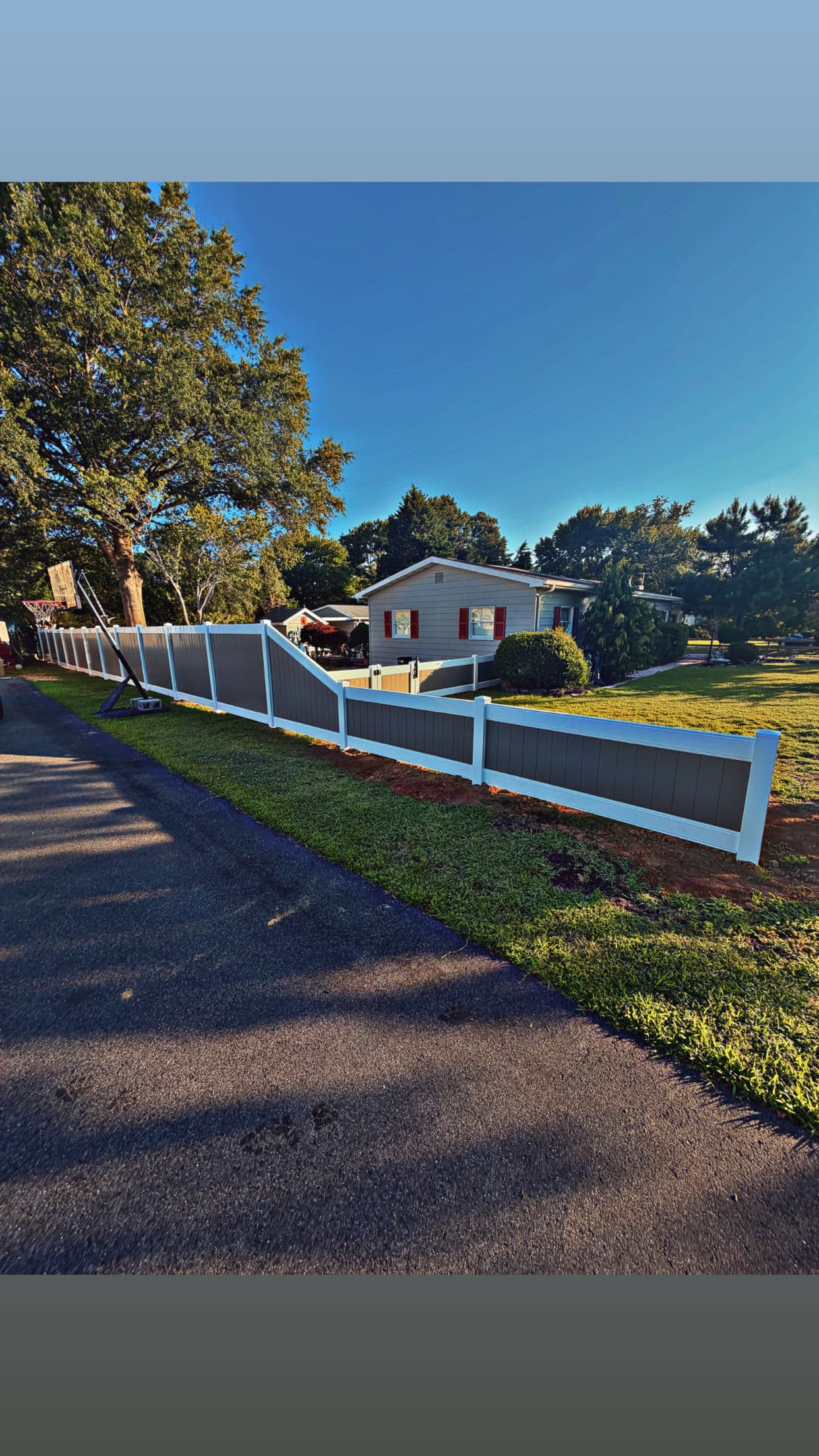 Two-Tone Vinyl Fence with a Stepped Slope and Clean Gate Finish